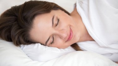 Huzur içinde uyuyor, beyaz rahat yatak, gülümseyen genç kadın yumuşak yastık üzerinde dinlenme şekerleme sabahları evde yatakta rahatlatıcı sakin tatlı rüyalar görmek mutlu güzel kızın yakın çekim