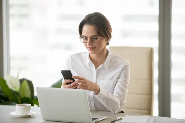 Feliz mujer de negocios leyendo noticias en el teléfono inteligente durante el trabajo offic —  Fotos de Stock