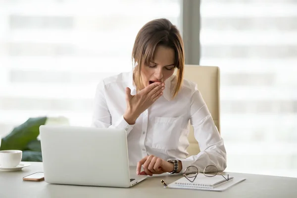 Erschöpfte Mitarbeiterin kontrolliert Wache im Büro — Stockfoto