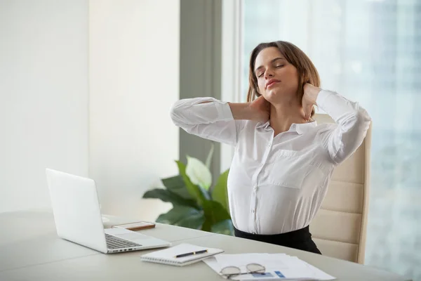 Cansado trabalhador feminino alongamento na cadeira relaxante depois de trabalhar d — Fotografia de Stock