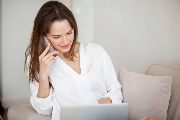 Smiling female talking on phone browsing web — Stock Photo, Image