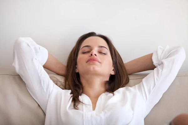 Спокійна жінка лежить руками над головою, розслабляючись вдома — стокове фото