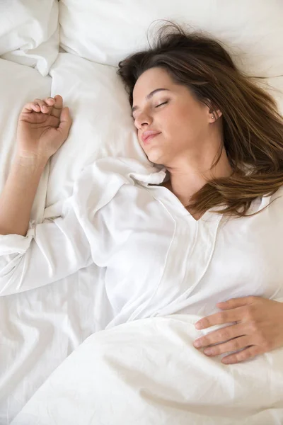 Спокійна дівчина розслабляється спить на м'яких подушках у спальні — стокове фото