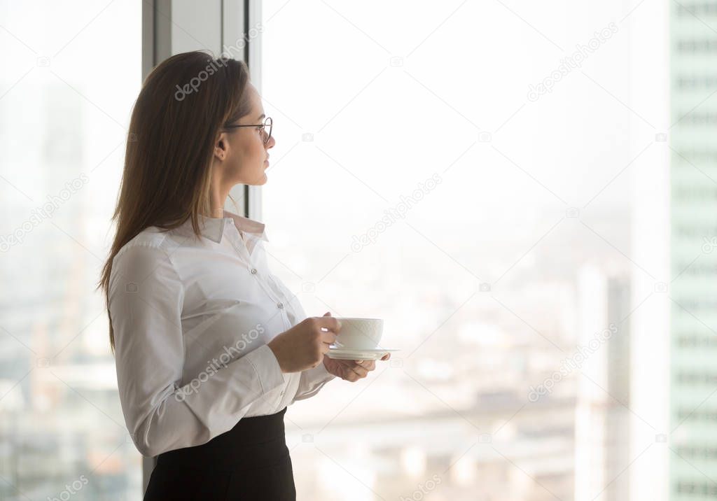 Thoughtful ceo enjoying view from window drinking coffee