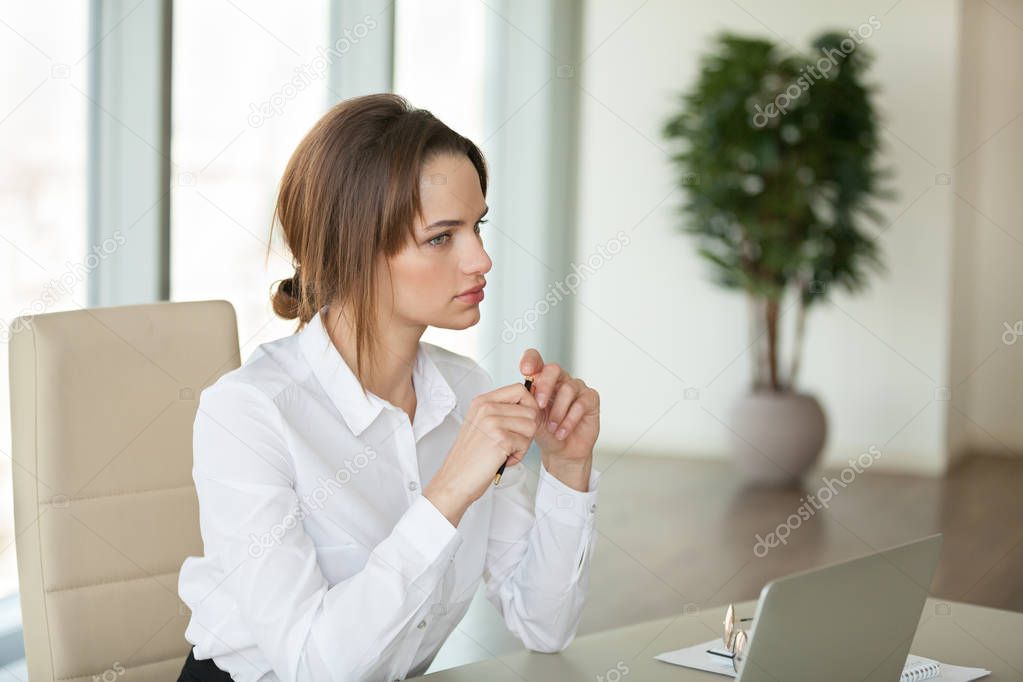 Focused female sitting at desk planning or considering new proje