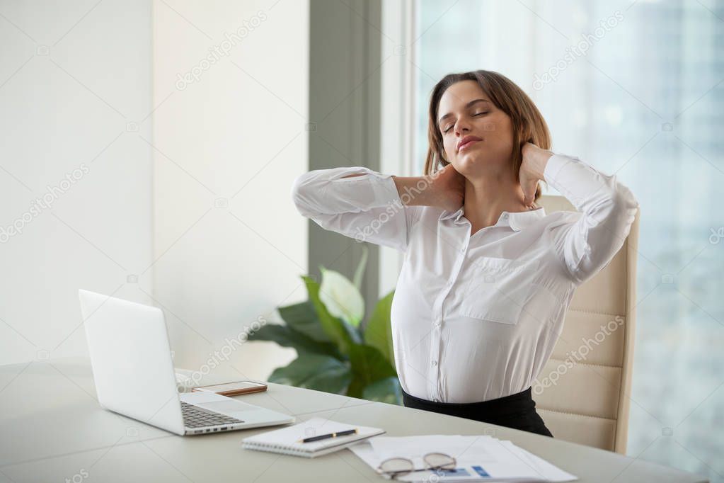 Tired female worker stretching in chair relaxing after working d