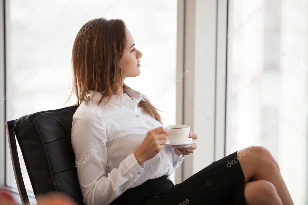 Confident female employee having coffee dreaming of future succe