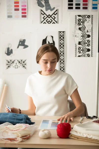 Serious female fashion designer choosing color swatch for new co — Stock Photo, Image