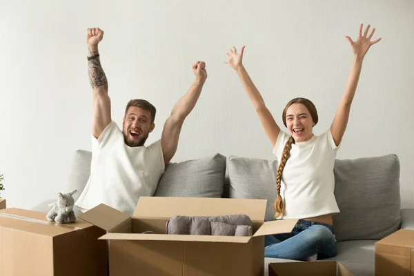 Emocionada pareja levantando las manos feliz de mudarse a nueva casa — Foto de Stock