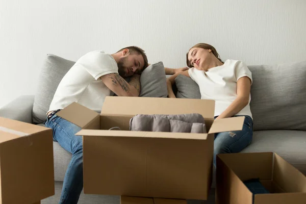 Väsynyt nuori pari rentouttava sohvalla siirtymässä uuteen taloon — kuvapankkivalokuva