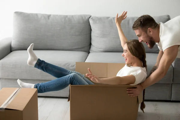 Feliz pareja montando en cajas que se divierten desempacando cajas — Foto de Stock