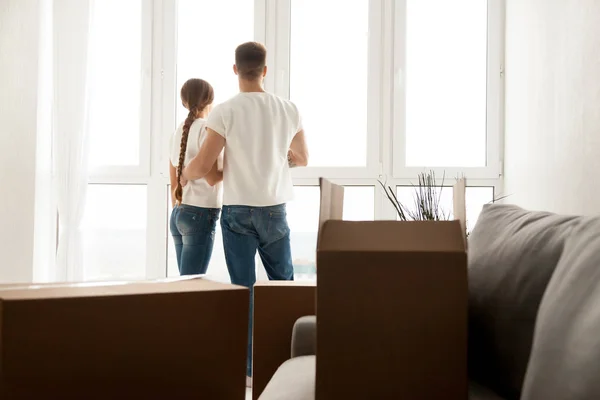 Couple looking through window planning future in new home — Stock Photo, Image