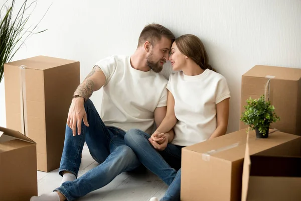 Spouses looking at each other sitting on floor while moving