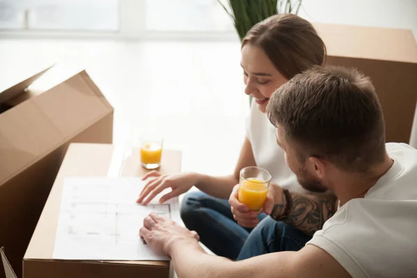Glückliches Paar diskutiert über Wohnungseinrichtung und trinkt Saft — Stockfoto