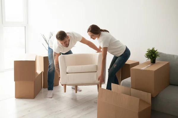 Junges Paar schleppt Stuhl in erste gemeinsame Wohnung — Stockfoto