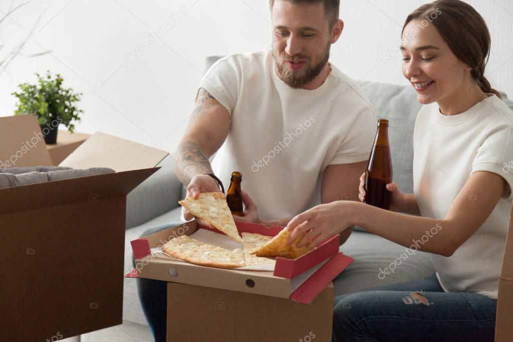 Happy couple eating pizza celebrating housewarming party