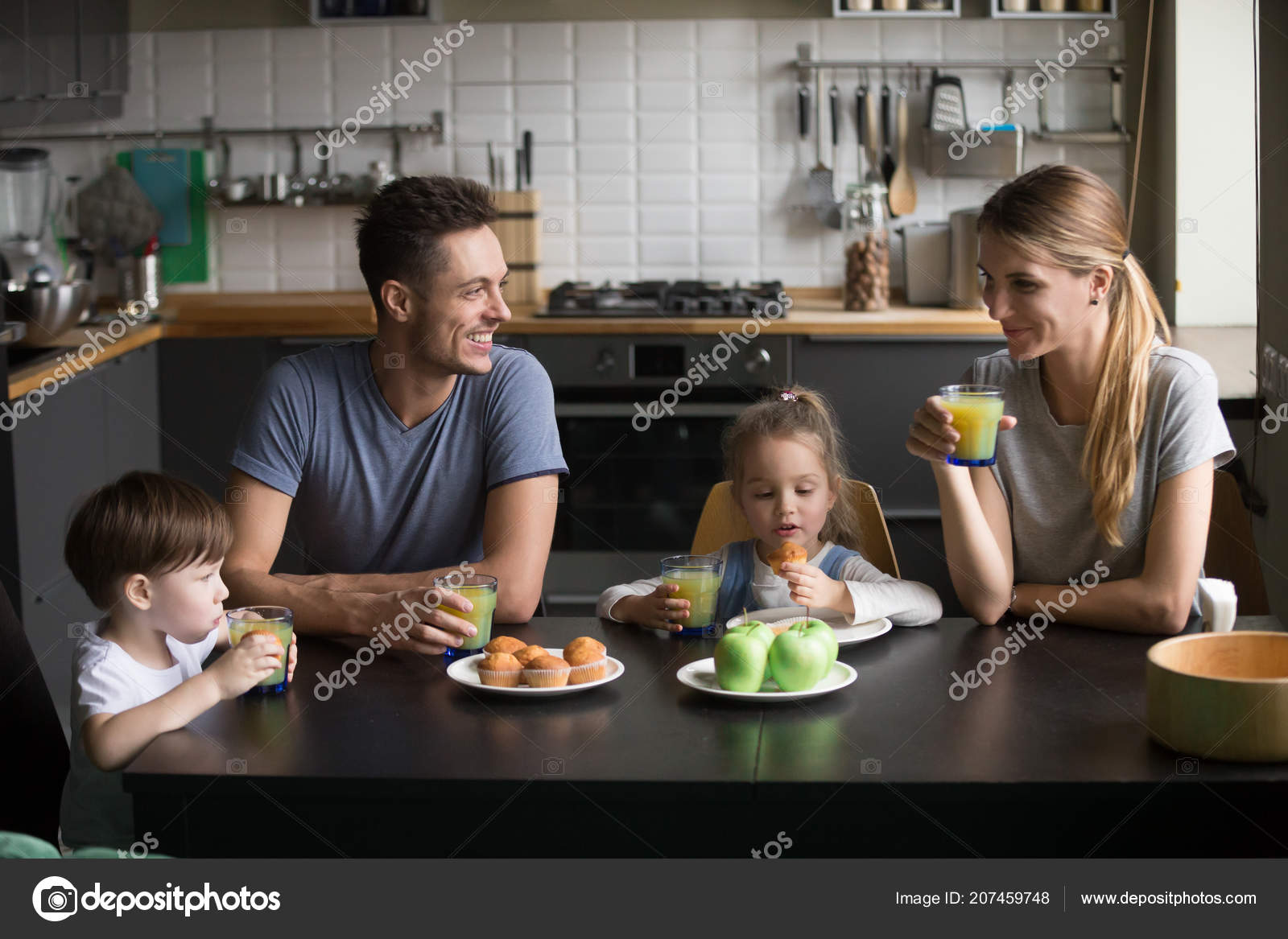 Happy Family And Kids Having Breakfast Sitting At Kitchen Table
