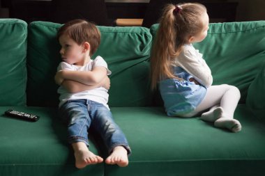 Upset siblings sitting on sofa ignoring each other after fight clipart