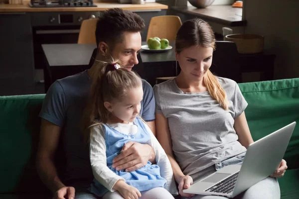 Семья с дочерью смотрят видео на ноутбуке вместе на диване — стоковое фото