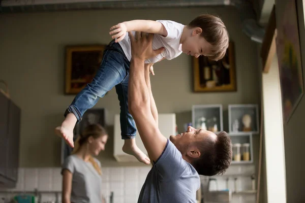 幸せなお父さんの家で一緒に遊んで楽しんでいる息子を持ち上げる — ストック写真