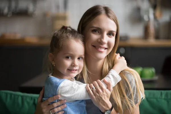 Usměvavá maminka objímá roztomilý přijaté dítě dcera při pohledu na camer — Stock fotografie