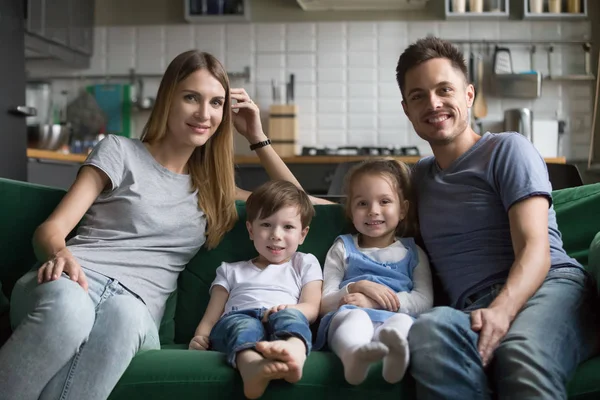 Портрет счастливых родителей с милыми детьми, сидящими на диване — стоковое фото