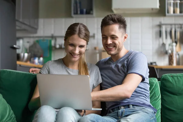 Счастливая пара смеется глядя на ноутбук вместе смотреть смешно — стоковое фото