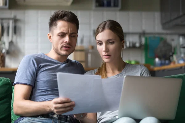 Pareja seria confundida revisando facturas nacionales con papeles y — Foto de Stock