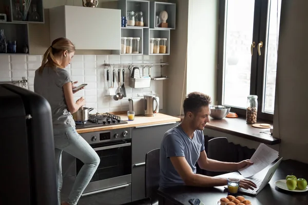 Genç çift mutfakta laptop ve smartphone kullanarak — Stok fotoğraf