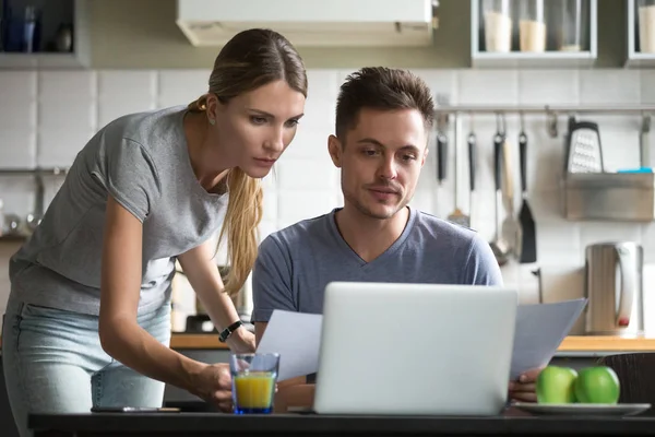 Pareja seria sosteniendo documentos utilizando la aplicación en línea para pa — Foto de Stock