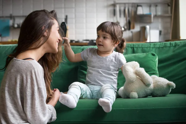 Niña cepillando madres pelo divertirse jugando en casa — Foto de Stock