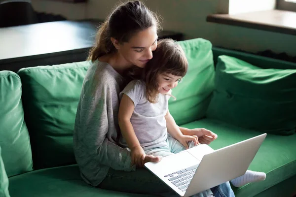Madre feliz con hija del niño que se divierte en línea con el ordenador portátil —  Fotos de Stock