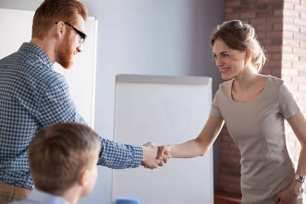 Millennial male worker handshaking female partner or colleague — Stock Photo, Image