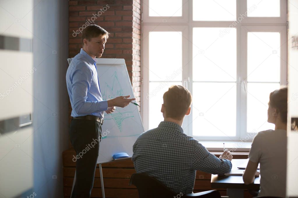 Serious male speaker presenting business strategy on flipchart 