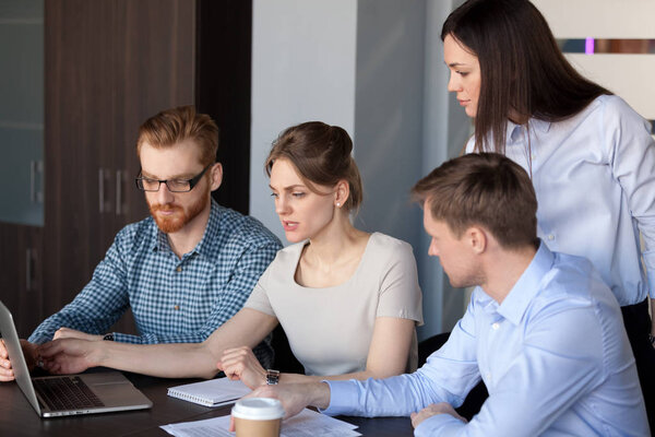 Diverse employees coworking at laptop during team meeting