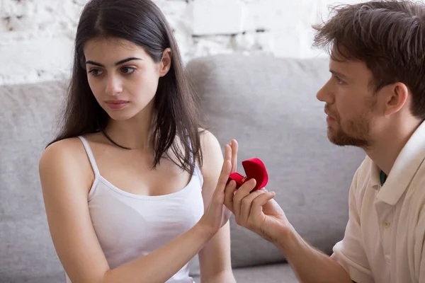 Dissatisfied woman rejecting marriage ring from boyfriend