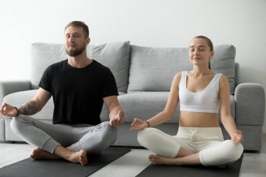 Sakin genç çift lotus pozisyonu paspaslar üzerinde meditasyon