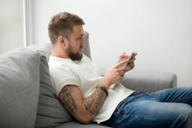 Bin yıllık adam örümcek ağı browsing tablet tutan kanepede oturan