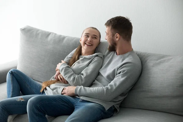 Улыбающаяся пара обнимается расслабляясь на уютном диване — стоковое фото