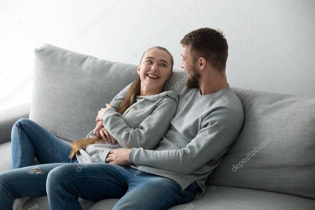 Smiling couple hugging relaxing at cozy sofa