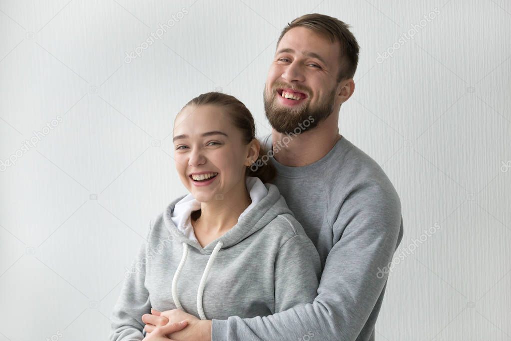 Portrait of happy millennial couple posing in own apartment
