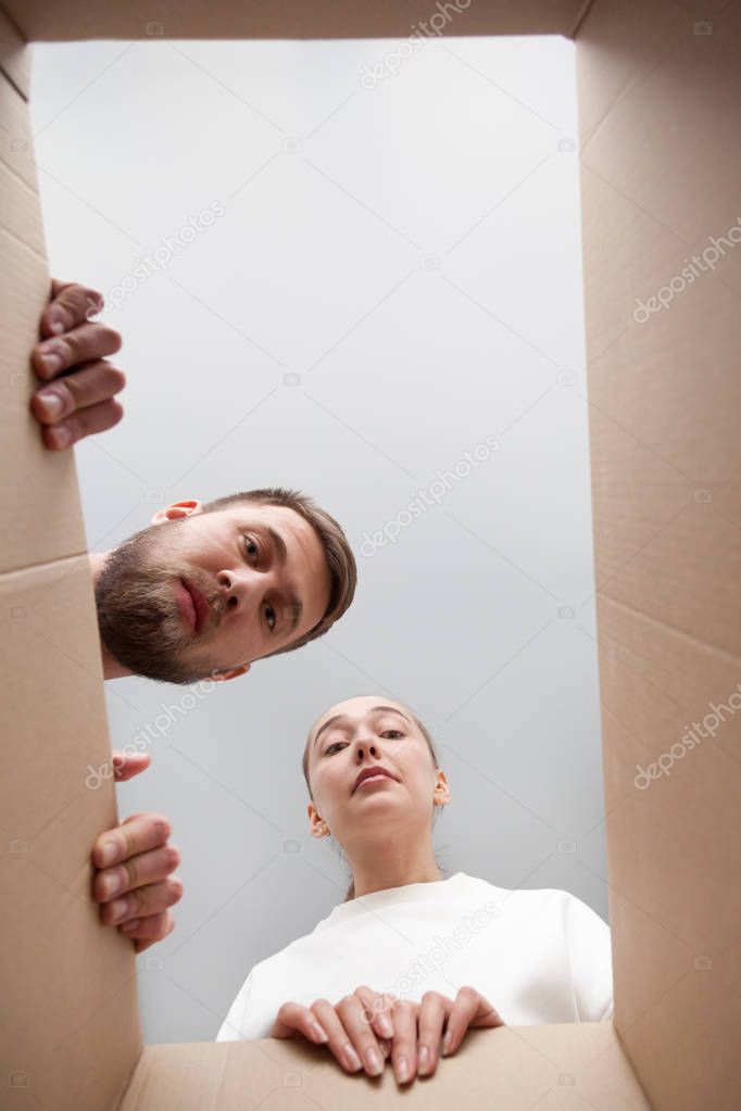 Frustrated couple looking inside parcel disappointed with order