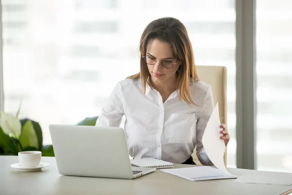 Seriøs forretningskvinne som jobber med laptop-dokumenter som analyserer pr. – stockfoto