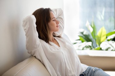 Relaxed woman resting breathing fresh air at home on sofa clipart
