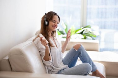 Gülümseyen genç kadın smartpho müzik dinlerken kulaklık