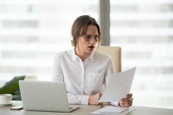 Shocked astonished businesswoman surprised by reading unexpected