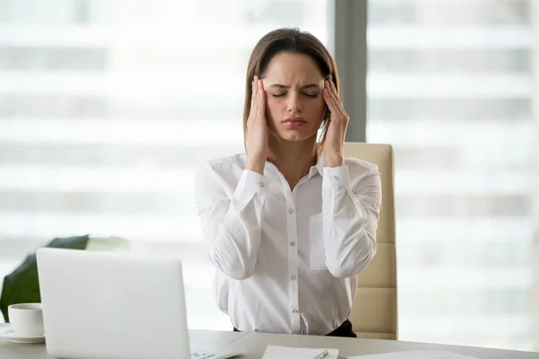 Стресована розчарована жінка працівник відчуває головний біль або мігрень — стокове фото