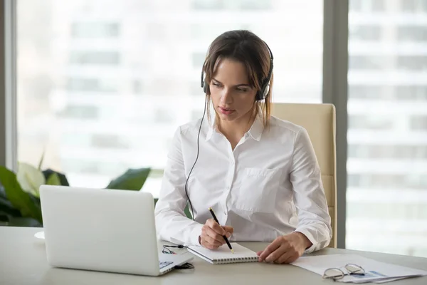 Serious businesswoman in headphones watching webinar on laptop m — Stock Photo, Image