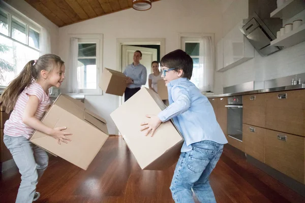 Glada barn ha roligt att föra in lådor till nytt hus — Stockfoto