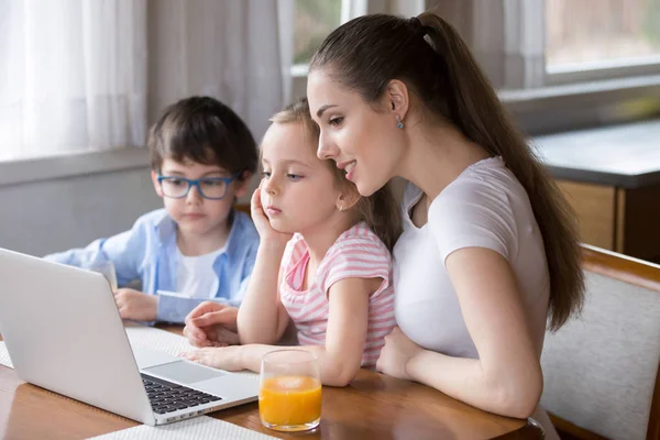 Joven mamá ver dibujos animados en el ordenador portátil con hija e hijo —  Fotos de Stock